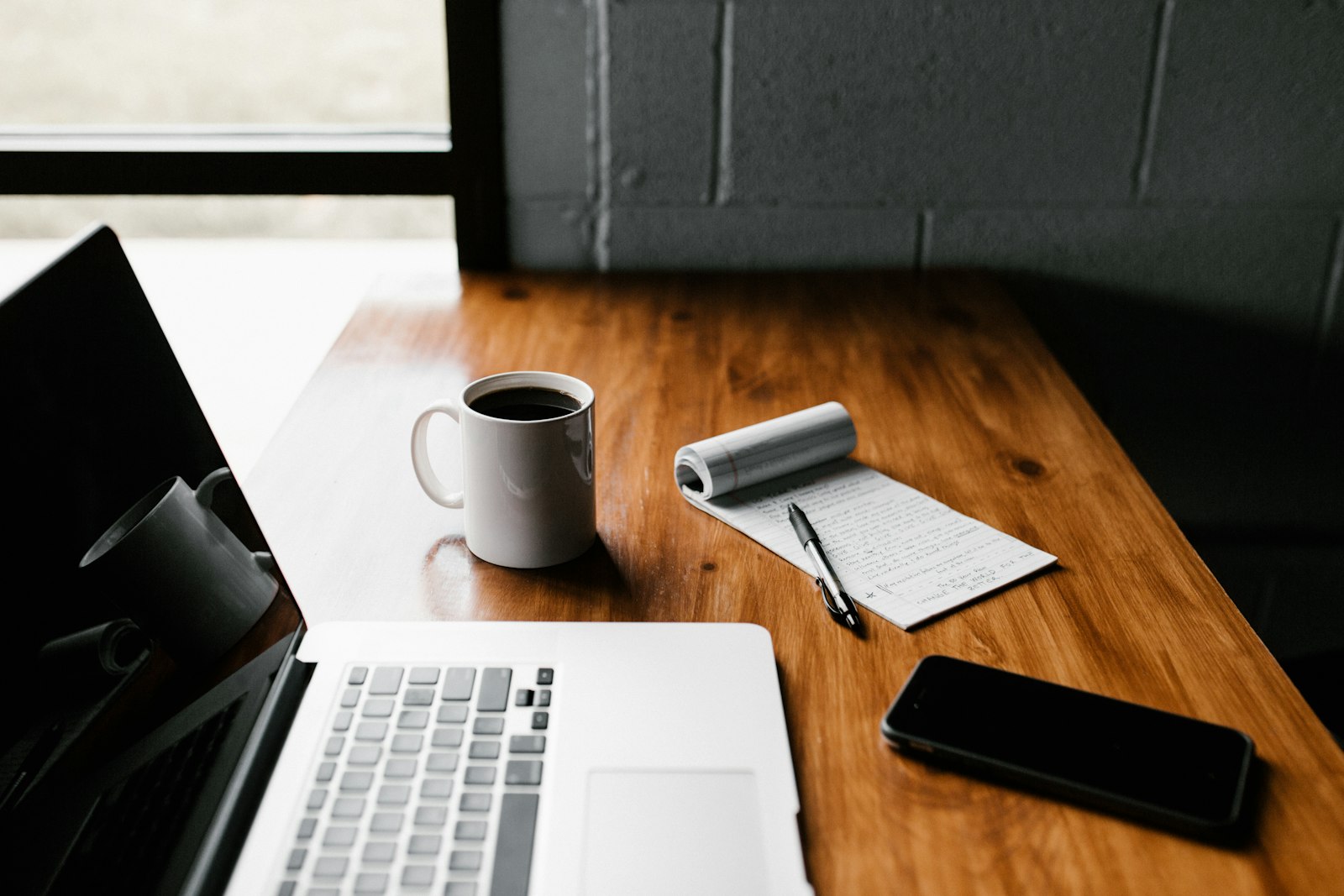 Laptop, notebook and coffee on a desk set up for writing content